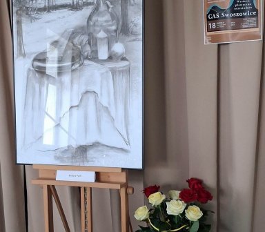 na sztaludze obraz szkic, na podłodze stoi wazon z kwiatami, po prawej plakat wydarzenia