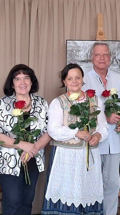 Zaproszeni goście, uczestnicy wystawy, artysci stoją z różami